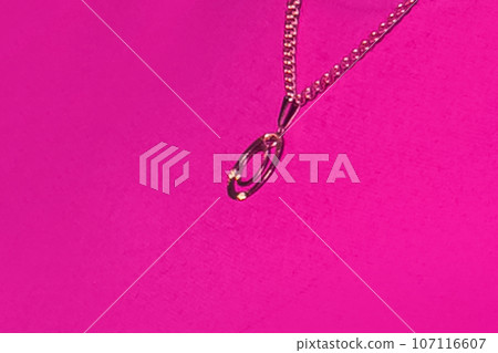 Gold pendant decoration chain close-up macro soft focus on pink background 107116607