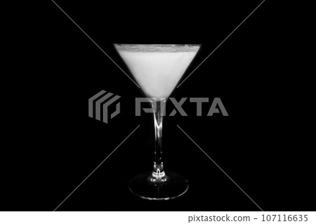 A martini glass with a white alcoholic beverage on an black background 107116635