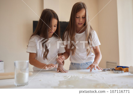 little girl is helping to bake in a messy kitchen. little girl is helping to bake in a messy kitchen. 107116771