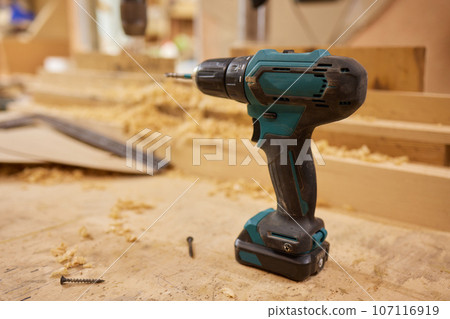 close up of a carpenter screwed a hinge on a wooden plank. 107116919