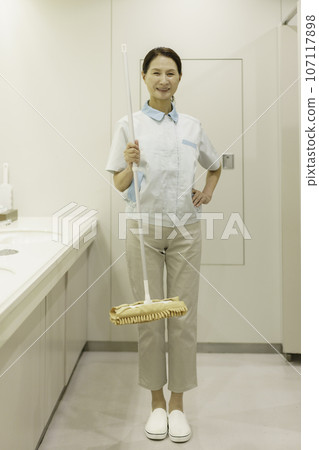 一位高級女清潔工站在辦公室洗手間、手持拖把、垂直位置的肖像 107117898