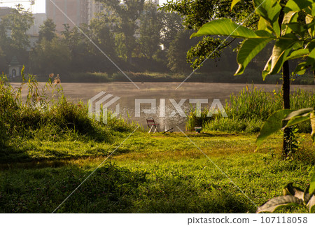 Fisherman's chair and fishing rod in the background over the lake at dawn. Fisherman's chair and fishing rod in the background over the lake at dawn. 107118058