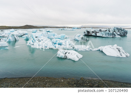 Luminous blue icebergs floating in glacial lagoon with background of glacier mountain. Luminous blue icebergs floating in glacial lagoon with background of glacier mountain. 107120490