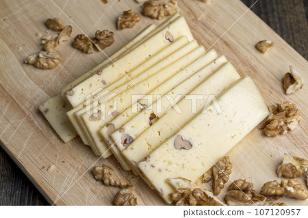 Sliced piece of milk cheese with walnuts Sliced piece of milk cheese with walnuts 107120957