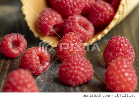 Ripe red raspberries in a crispy waffle cone 107121153