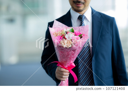 一個穿著西裝的男人拿著一束鮮花 107121408