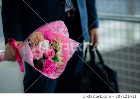 A man in a suit holding a bouquet of flowers 107121411