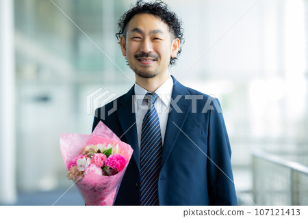A man in a suit holding a bouquet of flowers 107121413