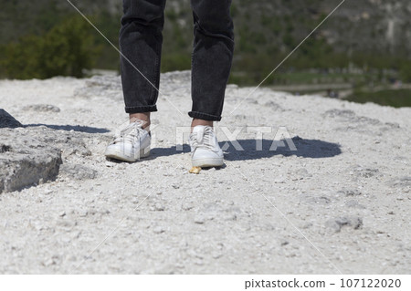 Human feet in shoes on a stone surface. 107122020
