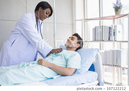 African doctor morning visit patient using stethoscope checking lung breath and heart pulse male in hospital African doctor morning visit patient using stethoscope checking lung breath and heart pulse male in hospital 107122212