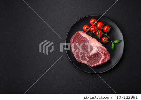 Fresh raw beef striploin steak with salt, spices and herbs 107122961