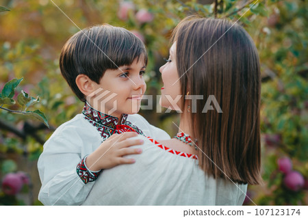 Portrait of family - 4 years old boy embracing mother in apple orchard. Tender. Portrait of family - 4 years old boy embracing mother in apple orchard. Tender. 107123174