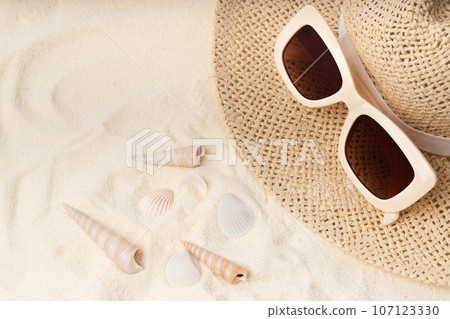 Modern trendy neutral beige sunglasses with orange brown glasses on straw rattan hat. 107123330