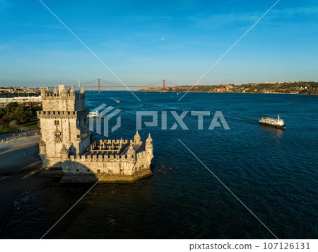 Aerial view of Belem Tower famous tourist landmark of Lisboa and tourism attraction on the bank of the Tagus River (Tejo) with tourist boat at sunset. Lisbon, Portugal 107126131