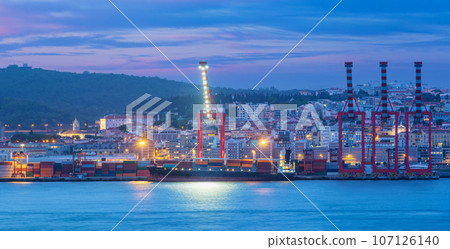 View of Lisbon port with moored sea container ship with port cranes in the evening twilight over Tagus river. Lisbon, Portugal View of Lisbon port with moored sea container ship with port cranes in the evening twilight over Tagus river. Lisbon, Portugal 107126140