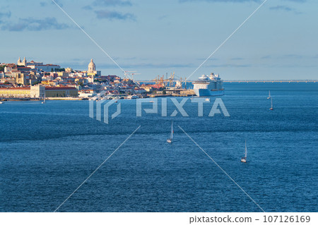 View of Lisbon over Tagus river from Almada with yachts tourist boats and moored cruise liner on sunset. Lisbon, Portugal View of Lisbon over Tagus river from Almada with yachts tourist boats and moored cruise liner on sunset. Lisbon, Portugal 107126169