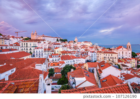 View of Lisbon famous view from Miradouro de Santa Luzia tourist viewpoint over Alfama old city district on sunset with dramatic overcast sky. Lisbon, Portugal. 107126190