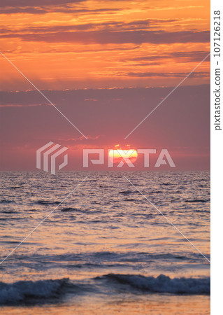 Ocean waves on sunset with setting sun background Ocean waves on sunset with setting sun background 107126218