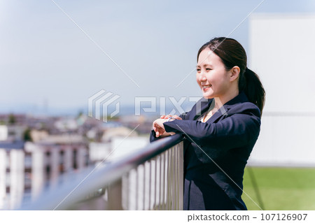 Business woman looking at the view from the rooftop / Local city / Region / Migration / Rural life / Rural migration Business woman looking at the view from the rooftop / Local city / Region / Migration / Rural life / Rural migration 107126907