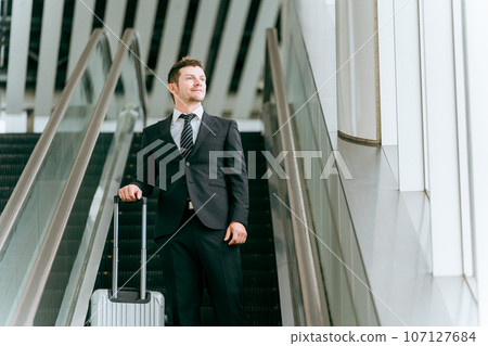 Western businessman going on a business trip with a suitcase, overseas business trip, overseas assignment, trading company, trade (escalator) Western businessman going on a business trip with a suitcase, overseas business trip, overseas assignment, trading company, trade (escalator) 107127684