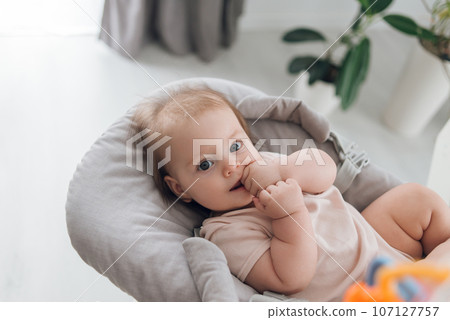 The baby lies in a transforming chair or in a growing chair in a bright room. High quality photo 107127757