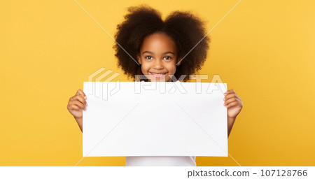 cute dark-skinned girl smiling and holding a piece of white layout paper on a yellow background. High quality photo cute dark-skinned girl smiling and holding a piece of white layout paper on a yellow background. High quality photo 107128766