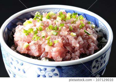 一張黑色背景下鮪魚塔塔基碗的照片，上面有很多蔥 107129010