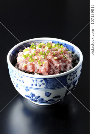 A photograph of a tuna tataki bowl topped with lots of green onions against a black background 107129015