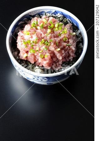 黑色背景下鮪魚塔塔基碗的頭頂照片,上面有很多蔥 黑色背景下鮪魚塔塔基碗的頭頂照片,上面有很多蔥 107129042