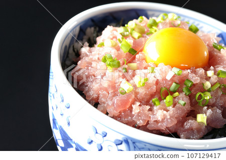 黑色背景下拍攝的鮪魚塔塔基碗,上面放著蔥和蛋黃 黑色背景下拍攝的鮪魚塔塔基碗,上面放著蔥和蛋黃 107129417