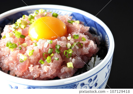 黑色背景下拍攝的鮪魚塔塔基碗,上面放著蔥和蛋黃 黑色背景下拍攝的鮪魚塔塔基碗,上面放著蔥和蛋黃 107129418