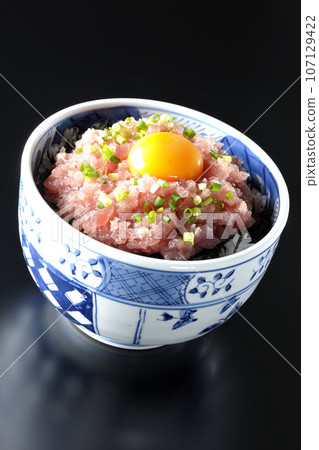 黑色背景下拍攝的鮪魚塔塔基碗，上面放著蔥和蛋黃 107129422