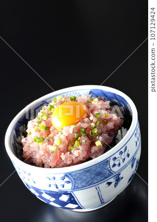 黑色背景下拍攝的鮪魚塔塔基碗,上面放著蔥和蛋黃 黑色背景下拍攝的鮪魚塔塔基碗,上面放著蔥和蛋黃 107129424