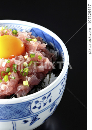 黑色背景下拍攝的鮪魚塔塔基碗,上面放著蔥和蛋黃 黑色背景下拍攝的鮪魚塔塔基碗,上面放著蔥和蛋黃 107129427