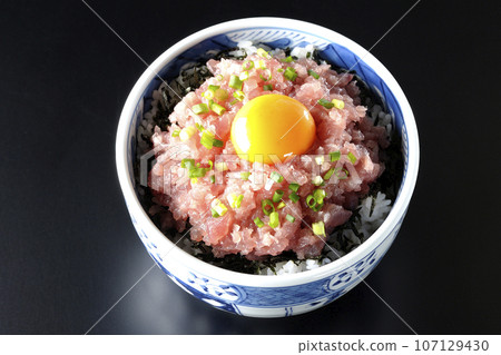 黑色背景下鮪魚塔塔基碗的頭頂照片，上面放著蔥和蛋黃 107129430