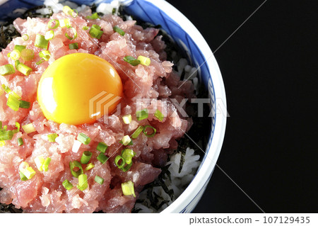 黑色背景下鮪魚塔塔基碗的頭頂照片,上面放著蔥和蛋黃 黑色背景下鮪魚塔塔基碗的頭頂照片,上面放著蔥和蛋黃 107129435