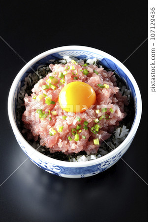 黑色背景下鮪魚塔塔基碗的頭頂照片，上面放著蔥和蛋黃 107129436