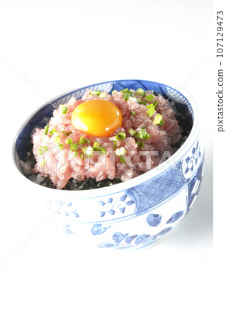 Tuna tataki bowl topped with green onion and egg yolk photographed against a white background Tuna tataki bowl topped with green onion and egg yolk photographed against a white background 107129473