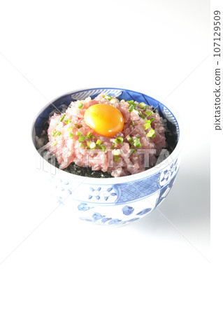 Tuna tataki bowl topped with green onion and egg yolk photographed against a white background Tuna tataki bowl topped with green onion and egg yolk photographed against a white background 107129509