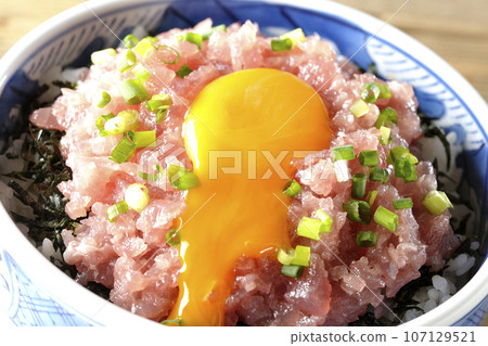 Crack the egg for the tuna tataki bowl topped with green onion and egg yolk. 107129521