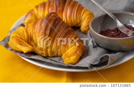 Brioche croissants on a plate with a small bowl of jam 107131665