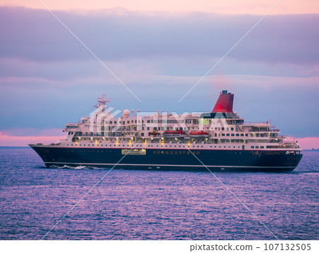 A luxury cruise ship departing from Kutsugata Port at dusk, photographed from Kutsugata Misaki Park on Rishiri Island in the Sea of Japan off the southwest coast of Wakkanai City, Hokkaido. 107132505