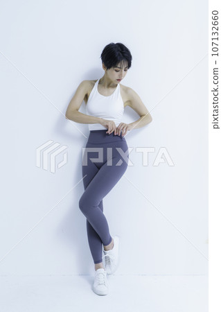 Portrait of a young woman wearing yoga wear against a white background, vertical position 107132660