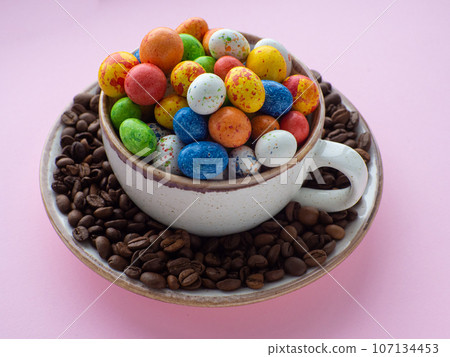 Mug full of color eggs on plate with coffee beans on background with copy space Mug full of color eggs on plate with coffee beans on background with copy space 107134453