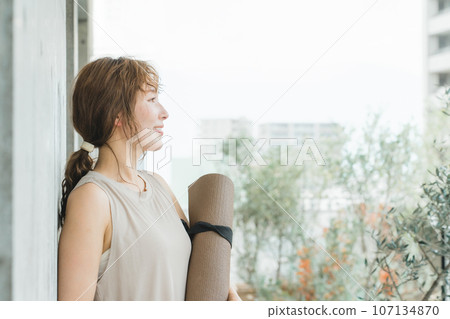 A woman who is a yoga instructor with a yoga mat, a woman who does yoga and Pilates 107134870