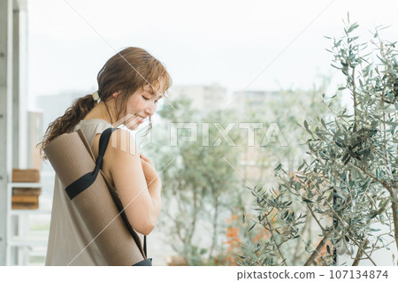 一個帶著瑜珈墊的瑜珈教練的女人,一個做瑜珈和普拉提的女人 一個帶著瑜珈墊的瑜珈教練的女人,一個做瑜珈和普拉提的女人 107134874