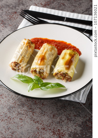 Baked leek stuffed with beef, rice, cheese and vegetables served with tomato sauce close-up in a plate. Vertical Baked leek stuffed with beef, rice, cheese and vegetables served with tomato sauce close-up in a plate. Vertical 107136021