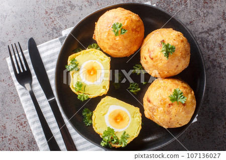 Balls of mashed potatoes stuffed with boiled egg and then fried close-up in a plate. Horizontal top view 107136027