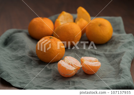 Organic tangerines on a linen napkin on a wood table Organic tangerines on a linen napkin on a wood table 107137935