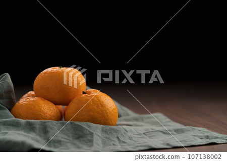 Organic tangerines on a linen napkin on a wood table Organic tangerines on a linen napkin on a wood table 107138002
